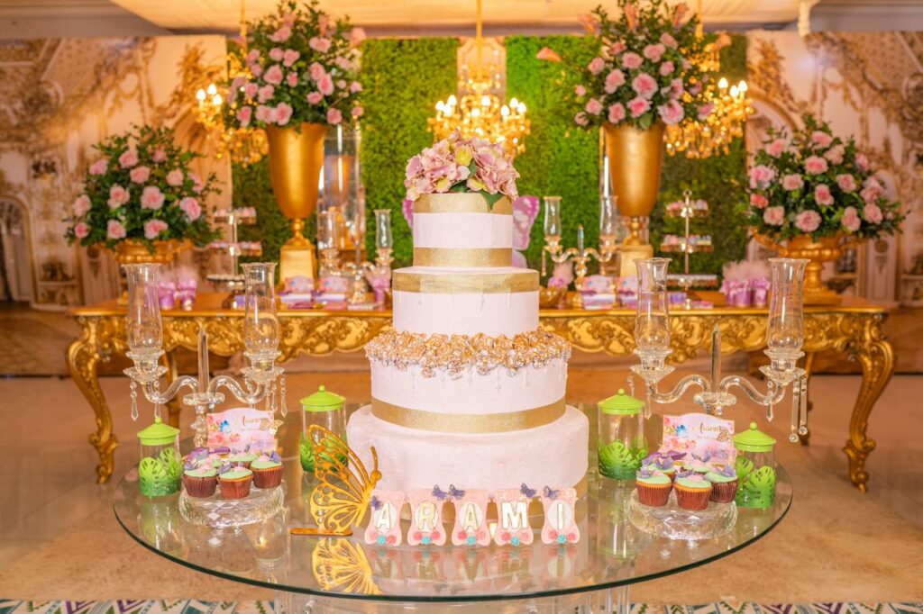 A beautifully decorated quinceañera venue featuring a lavish cake and floral arrangements with golden accents.