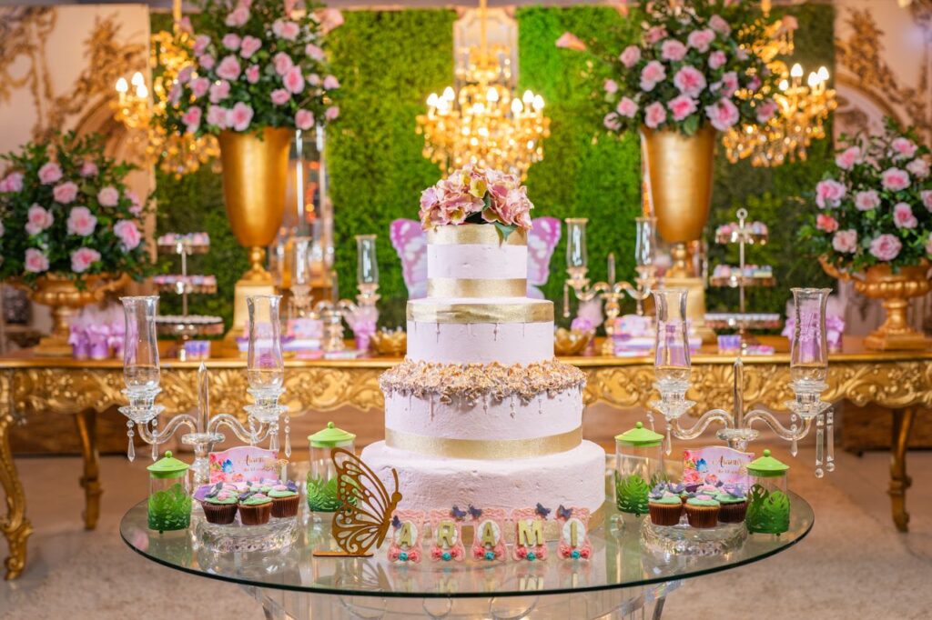 Luxurious quinceañera setup with a grand cake, florals, and upscale decor in a vibrant setting.