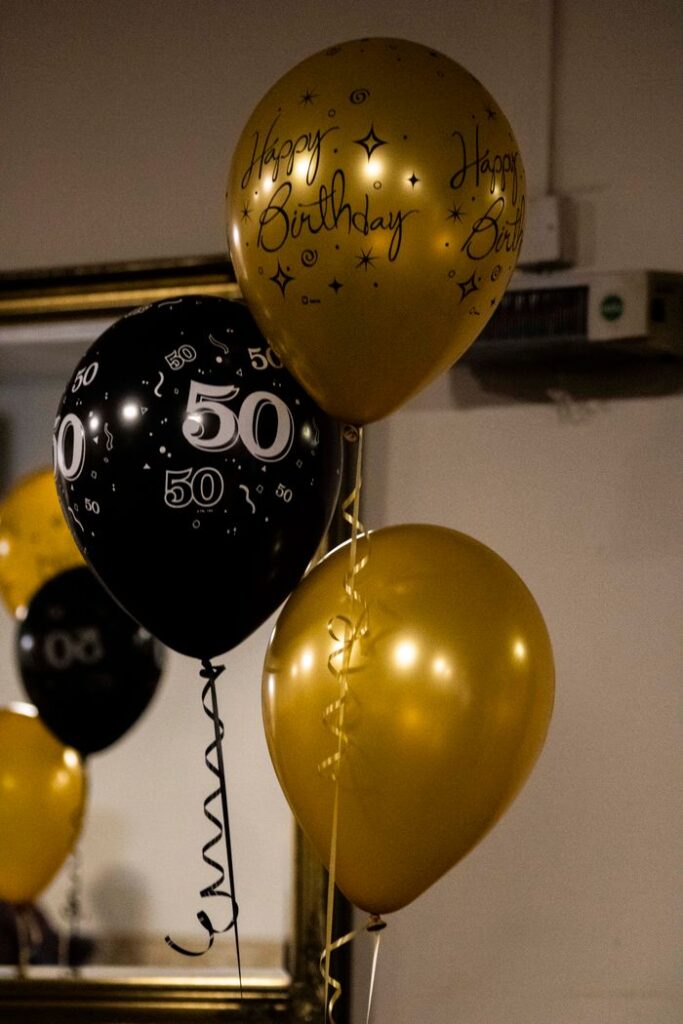 Elegant black and gold balloons celebrate a milestone 50th birthday indoors.