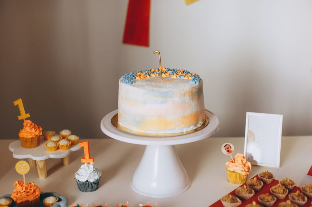 A beautifully decorated cake with cupcakes for a first birthday celebration.
