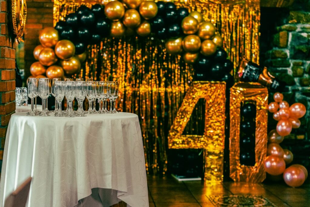Chic 40th birthday party setting with champagne flutes, balloons, and gold glitter backdrop.