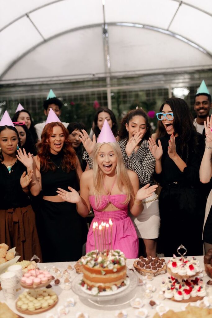 A group of friends celebrating a birthday with cake and party hats in a festive setting.