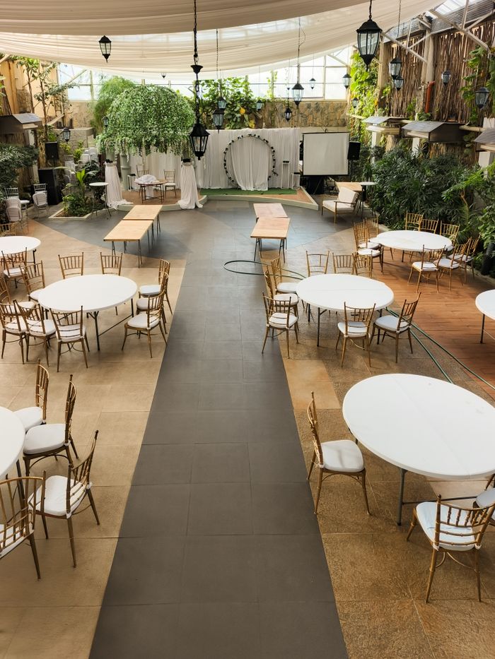 Spacious event venue with tables and chairs arranged for a gathering, featuring ample natural light.