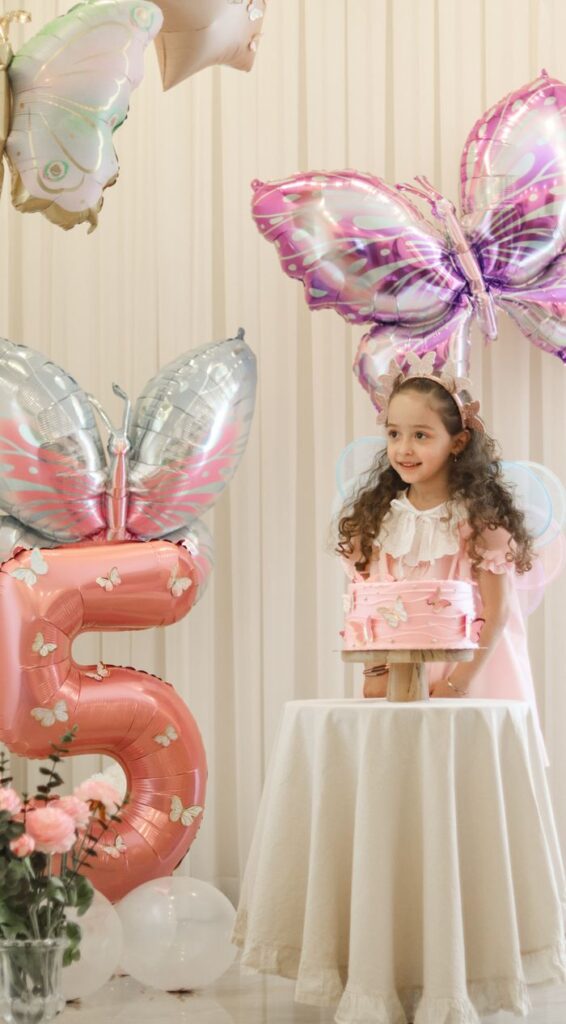 Young girl celebrates her fifth birthday in a whimsical butterfly-themed party.